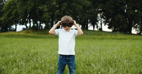 Child boy pilot with glasses looking to the sky, playing outdoors. Fantasy and Stock Footage 202211312