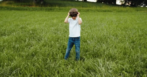Child boy pilot with glasses looking to the sky, playing outdoors. Fantasy and Stock Footage 202211390