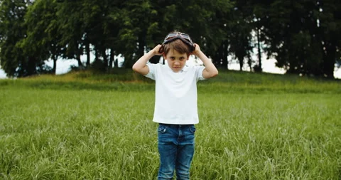Child boy pilot with glasses looking to the sky, playing outdoors. Fantasy and Stock Footage 202593643