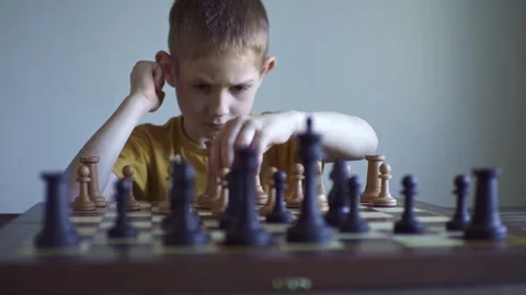 The child is a boy playing chess alone at the board Stock Footage 277942461