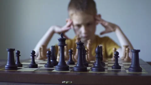The child is a boy playing chess alone at the board Stock Footage 277942464