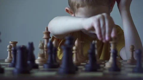 The child is a boy playing chess alone at the board Stock Footage 277942492