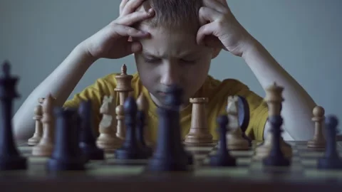 The child is a boy playing chess alone at the board Stock Footage 277942502