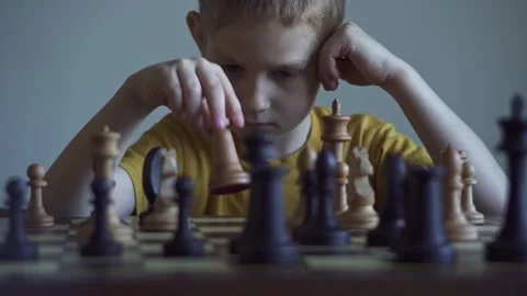 The child is a boy playing chess alone at the board Stock Footage 277942510
