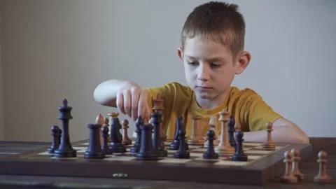 The child is a boy playing chess alone at the board Stock Footage 277942557