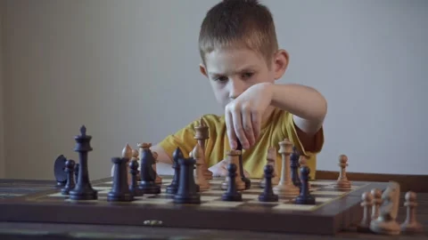The child is a boy playing chess alone at the board Stock Footage 277942581