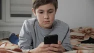 Child Boy Playing With Mobile Phone With Headphones At Home. Kid Using Stock Footage