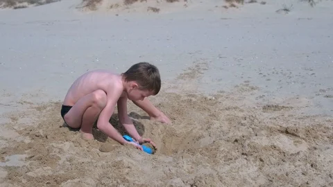 Child boy playing on sand beach digging shovel and trying to build sand tower. Stock Footage 116364137