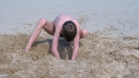 Child boy playing on sand beach digging shovel deep hole on summer vacation. Stock Footage 116364355