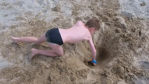 Child boy playing on sand beach digging shovel deep hole on summer vacation. Stock Footage 116364723