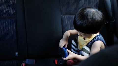 Child boy playing toy on back seat of car Stock Footage 94175880
