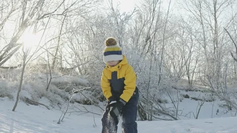 A child boy plays in winter throwing snow on a sunny frosty day Stock Footage 294346408