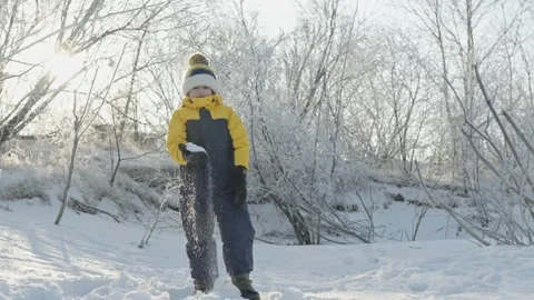 A child boy plays in winter throwing snow on a sunny frosty day Stock Footage 294346610