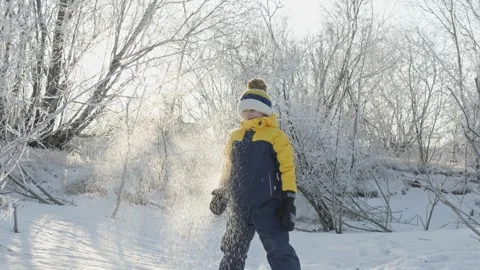 A child boy plays in winter throwing snow on a sunny frosty day Stock Footage 294346811