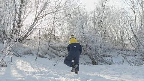 A child boy plays in winter throwing snow on a sunny frosty day Stock Footage 294347015