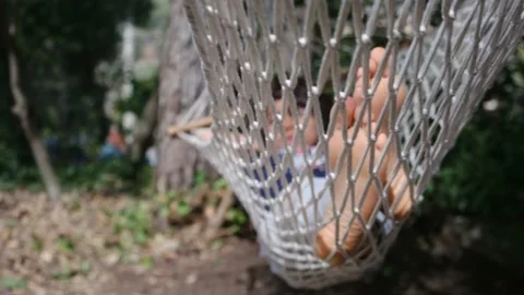 Child boy is resting in hammock in garden, in sunny summer day. Stock Footage 238367604