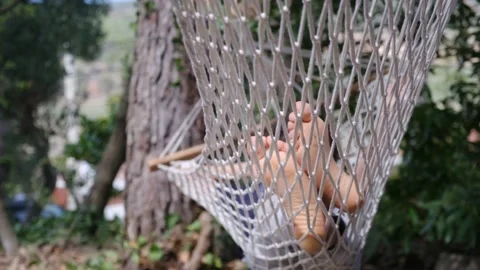 Child boy is resting in hammock in garden, in sunny summer day. Stock Footage 238367660