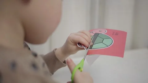Child boy sitting at table engrossed in cutting paper crafts colorful sheets Stock Footage 279515183