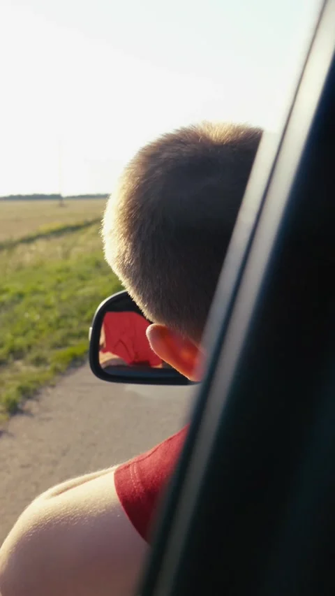 Child boy son enjoys summer day with his hand out car window, car rushing along Stock Footage 299735250