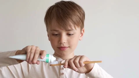 Child boy squeezes out white toothpaste onto toothbrush Stock Footage 187176565