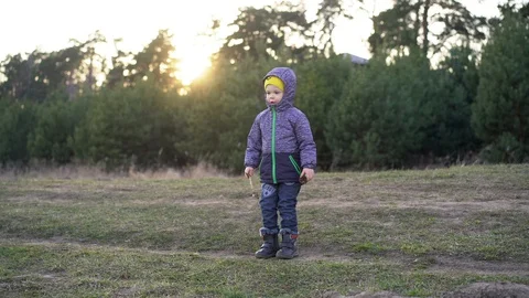 A child / boy stands on the path dressed in an autumn jacket Stock Footage 127767707