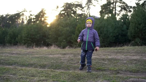 A child / boy stands on the path dressed in an autumn jacket Stock Footage 127767830