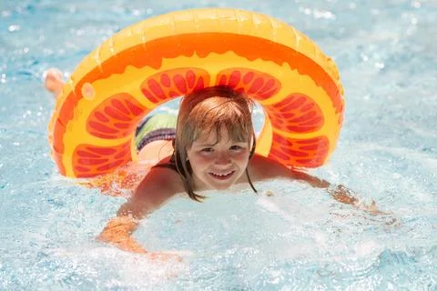 Child boy swim with float ring in swimming pool. Kids summer holidays and Stock Photos