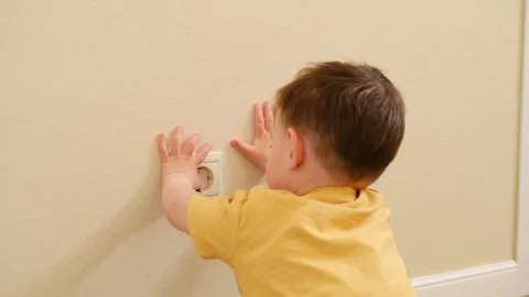 Child boy touching electric socket on wall. Dangerous behavior at home. Domestic Stock Footage 341856169