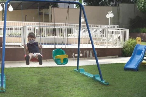 Child boy using a mask playing and swing in a playground Stock-Fotos