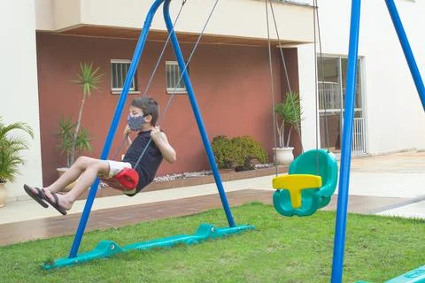 Child boy using a mask playing and swing in a playground Stock-Fotos