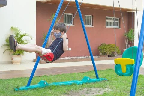 Child boy using a mask playing and swing in a playground 스톡 사진
