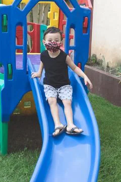 Child boy using a mask playing and sliding in a playground Stock Photos