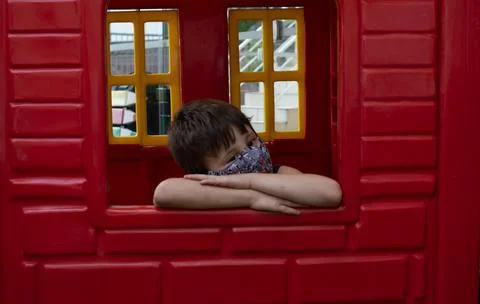 Child boy using a mask on a red wall looking to the camera Foto stock