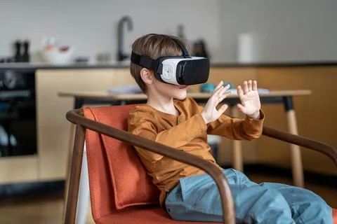 Child boy in VR headset device interacting with 3D world Stock Photos