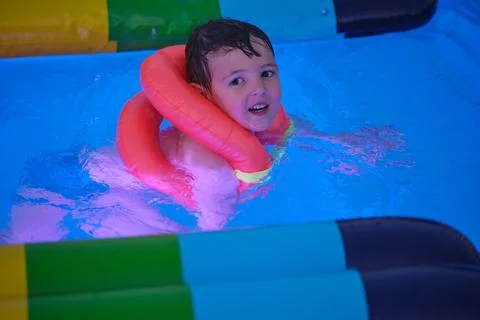 Child boy wearing inflatable neck ring swimming in blue pool. Toddler learnin Foto stock