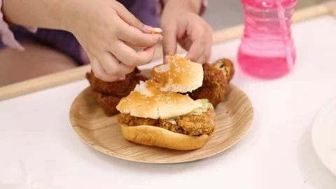 Child Breaking Chicken Burger Bun at Lunchtime Table Stock Footage 322209357
