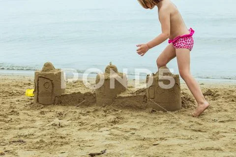 A child breaks a sand castle. Stock Photos