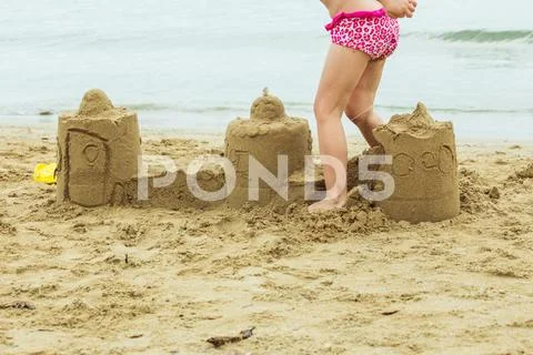 A child breaks a sand castle. Stock Photos