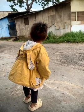 Child in Bright Yellow Jacket Exploring Rural Outdoor Setting on a Sunny Day Stock Photos