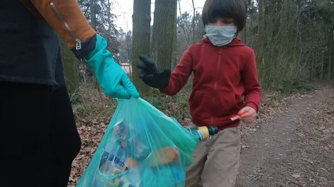 The child brought solid trash into a plastic bag. COVID 19 Video stock 127755908