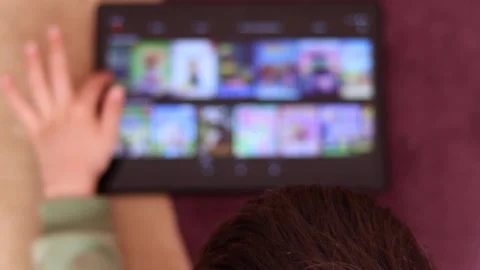 Child browsing movies on internet streaming services at the tablet pc Stock Footage 189358917