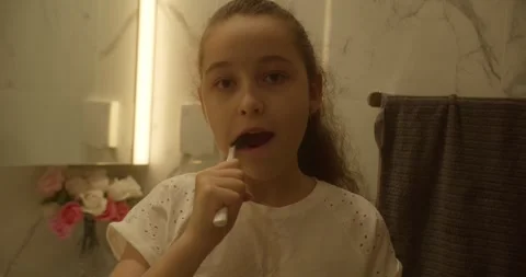 Child brushing teeth. A 12-year-old girl is brushing her teeth in the bathroom Stock Footage 307660982