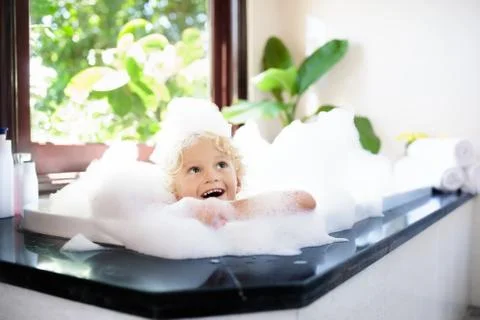 Child in bubble bath. Kid bathing. Baby in shower. Stock Photos
