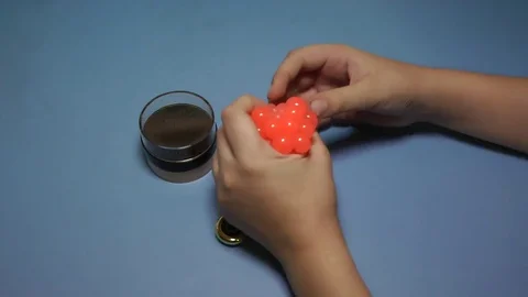 Child bugging in the hands of a soft ball on the blue background. 库存影片 83014525