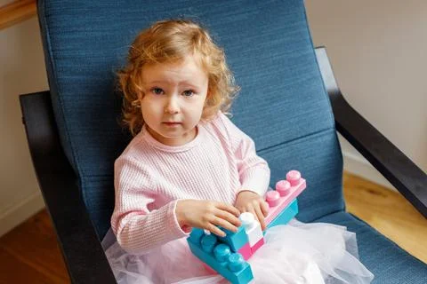 Child building with a construction toy while sitting in a chair at home Foto stock