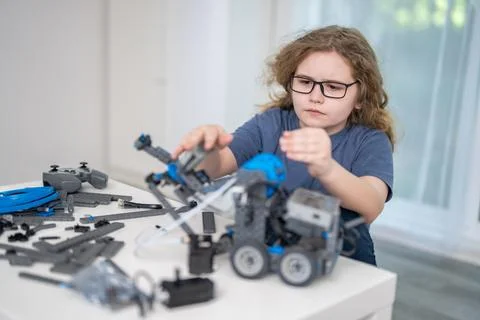 Child builds robot with focused hands. Child robotics supports smart STEM Stock Photos