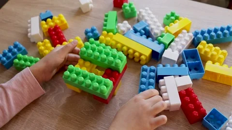 Child builds a tower with a constructor from colored bricks blocks on the table, Stock Footage 221337171