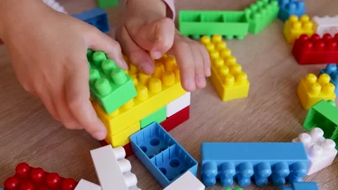 Child builds a tower with a constructor from colored bricks blocks on the table, Stock Footage 221337303