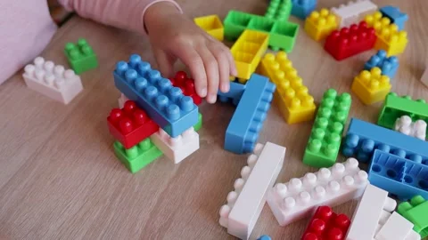 Child builds a tower with a constructor from colored bricks blocks on the table, Stock Footage 221337327
