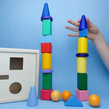 The child built a tower of multi-colored geometric shapes against the background Stock-Fotos